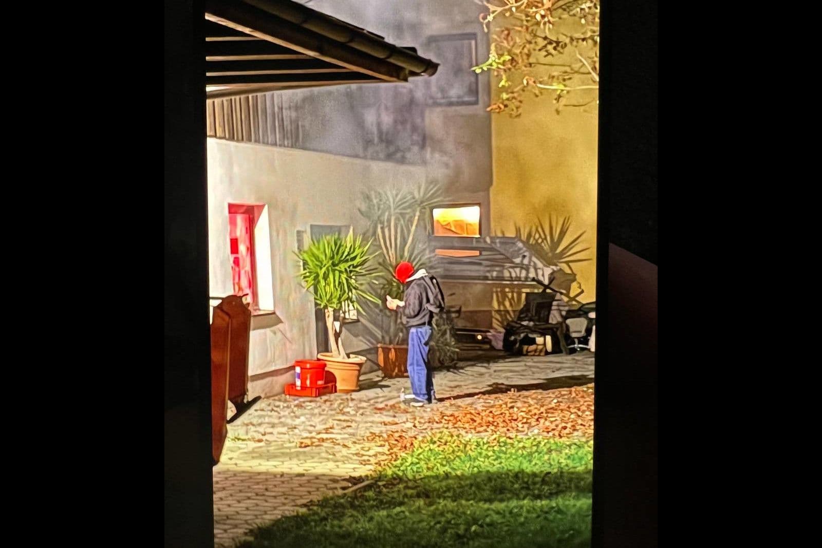 Auf dem Foto ist der mutmaßliche linksextreme Täter vor dem eingeschlagenen Fenster des Wahlkreisbüros zu sehen. Zu sehen sind auch Rauchschwaden und ein rotes Leuchten im Gebäude. © AfD